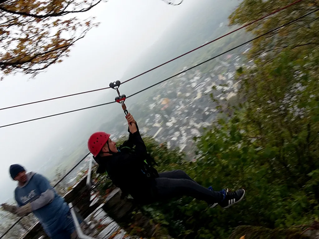 Person fährt mit gestreckten Armen an der Seilrutsche.